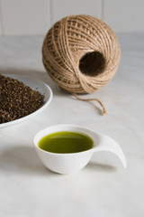 Natural hemp oil in a white ceramic spoon, hemp fiber and natural hemp thread.