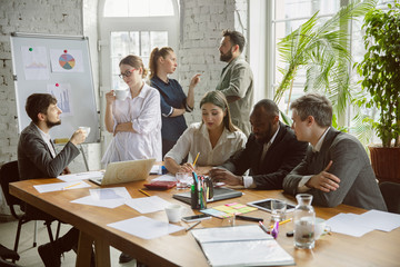 Coffee break. Group of young business professionals having a meeting. Diverse group of coworkers discuss new decisions, plans, results, strategy. Creativity, workplace, business, finance, teamwork.