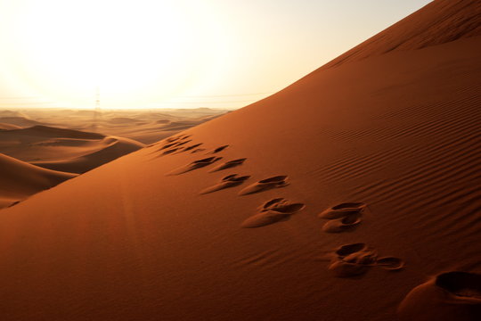 Footprints On The Sand Leading To Sunrise In The Desert For Bright Future Concept