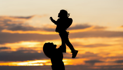 Silhouette of asian mother and daughter in sunset sky. mother and daughter are playing and proud happy together.