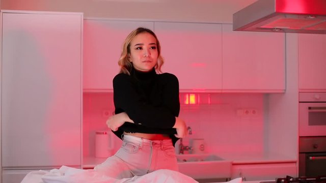 Girl, model sitting on the table takes off his black sweater, Looks to the side.