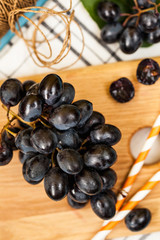 Black ripe juicy grapes close-up on a light wooden Board.