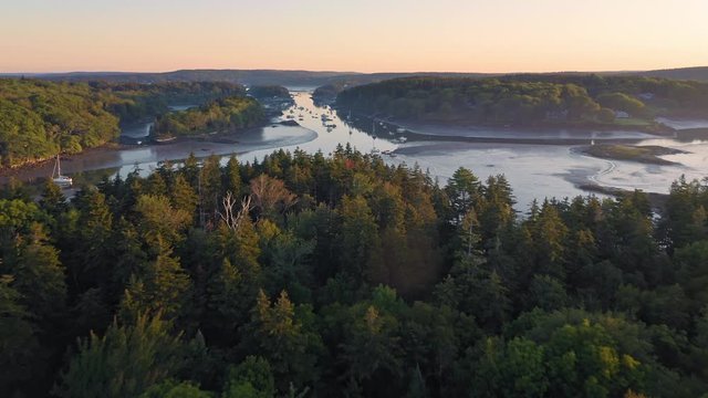 Aerial: tidal flats, estuary, ocean, Yachts, islands & forest at sunrise. Maine USA