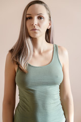 Graceful adult woman posing against beige wall.