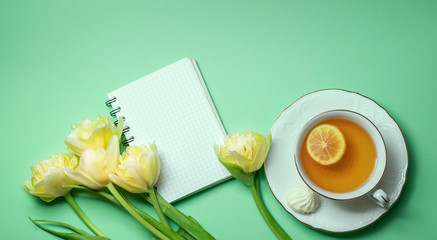 Bouquet of yellow tulips and a cup of tea with lemon close-up. Composition for Valentine's Day, birthday.