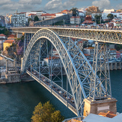 Side view of the metalwork of the famous Luis I Bridge in the Portuguese city of Porto against the backdrop of the city and blue sky