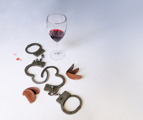 A drunken party, handcuffs on a cut-out background, chocolate, a glass of wine, drops of wine. A...