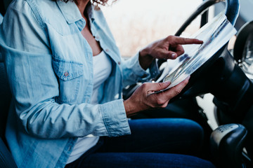 young beautiful woman reading a map in a car. travel concept