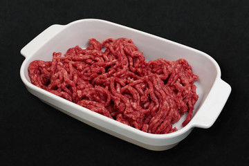 Fresh raw minced meat pork or beef on white tray or bowl on black stone cutting board background....