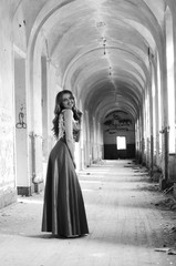 Naklejka premium Young beautiful short hair blonde woman in black climbing the stairs, black and white photo. Side view of elegant romantic mysterious lady with movie star look in interior with bricks walls