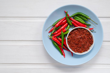 Hot chilli pepper sauce paste harissa, traditional Tunisia, Moroccan, Arabic cuisine adjika ,chili pepper spices and fresh red and green chilli peppers in blue plate, over white background. copy space