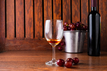 .Wine Glass and Wine Bottle with Red Grapes on Wooden Background