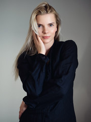 Fototapeta premium Young adorable blonde woman in black t-shirt dress posing next to window looking emotive and thoughtful