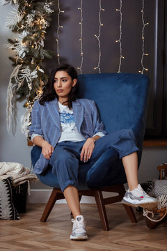 Beautiful Young Woman Wearing Blue Blazer Sitting In Blue Chair