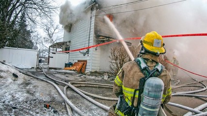 Firefighter spraying water on a house fire