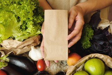 Organic vegetables in eco bag in market. Woman seller with craft paper bag and products in organic food store.  Healthy nutrition, Zero Waste, Lifestyle Concept. Banner for for web, design. Mock up