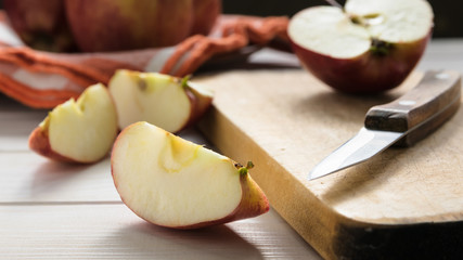 still life, slices of red chopped apple, on a wooden board on a white table