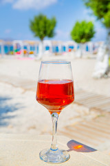 Wine on beach. A glass of tasty rose wine on sunny beach. Luxury vacation concept. 