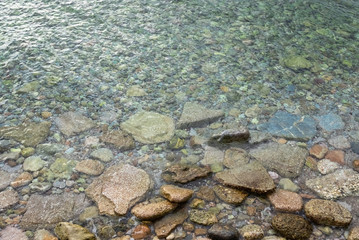 Abstract marine background with water covering stones and pebbles. Sea calm