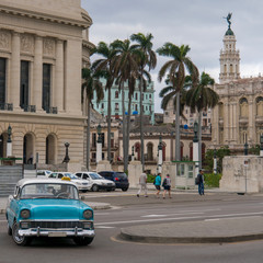 turning baby-blue classic cuban car in havana and the historic old buildings in the background, cuba