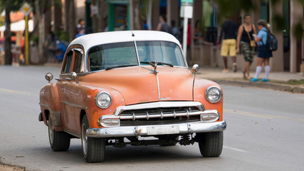 orange classic cuban car driving on a road