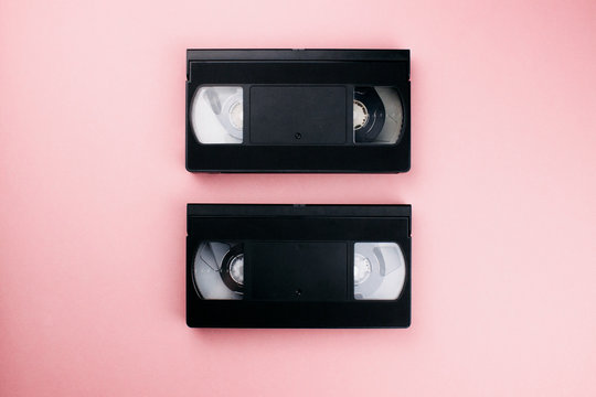 Retro VHS video cassette tapes flat lay on colorful pink background. Top view copy space. Creative fashion design in minimal 80-s style. Film, movie, cinema concept. Template for web. Stock photo.