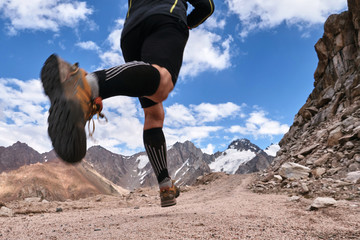 Closeup of feet with running shoes of a trailrunner man running in the mountains trail