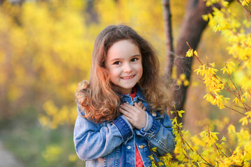 Child girl in denim jacket on a walk in the yellow autumn Park.