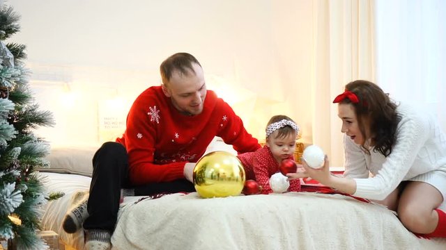 Happy family playing together: mother, father and 1 year old baby girl. Christmas holiday