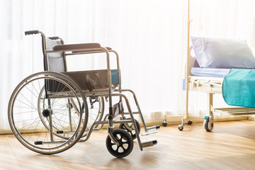 Empty wheelchair and bed in patient room, in hospital.