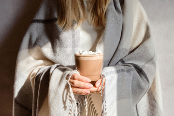 The girl holds a glass of hot cocoa in her hands. Cocoa with marshmallows closeup. Hot milk...