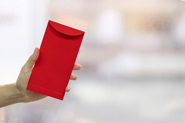 Hand holding red envelope or Ang pao. Chinese Lunar New Year celebrations concept