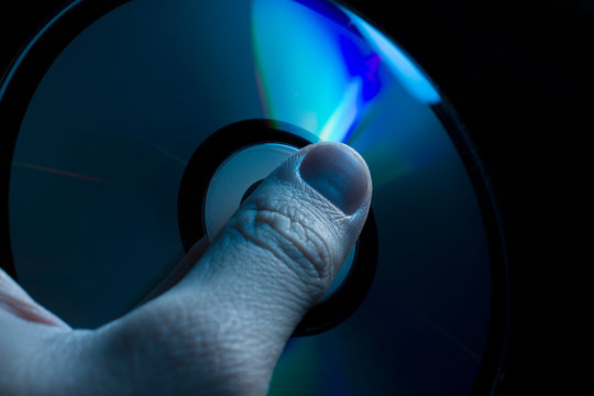 compact-disc in hand on a black background