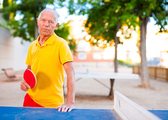 mature man posing with rackets at table tennis
