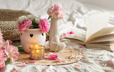 Candle and Vase with roses and peonies flowers and spring decor on the books