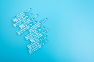 Ampules with a transparent preparation on a blue light background. Concept: drugs, injections, treatment, medicine.