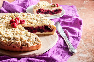 Homemade berry shortcrust pie with crumble on wooden board