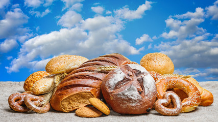 Fresh bread and bakery on sackcloth against the background cloudy sky, with space for text