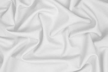 White woolen crumpled fabric with wrinkles and waves, closeup, background of crumpled tissue