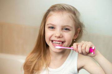 pretty blonde girl 7-8 years old brushing her teeth