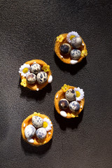 Easter eggs in basket with feather and tulips. On concrete gray background. Morning light. Rustic style. Top view.