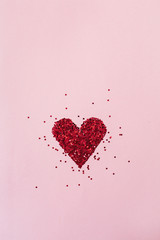 Heart symbol made of sparkles on pink background. Flatlay, top view Valentine's Day minimal holiday...