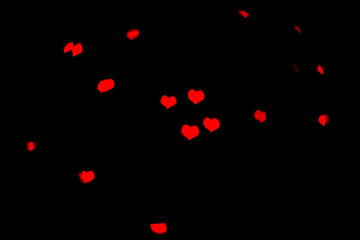 Naklejka na ściany i meble Blurred red lights in beautiful shape of the hearts on black background.