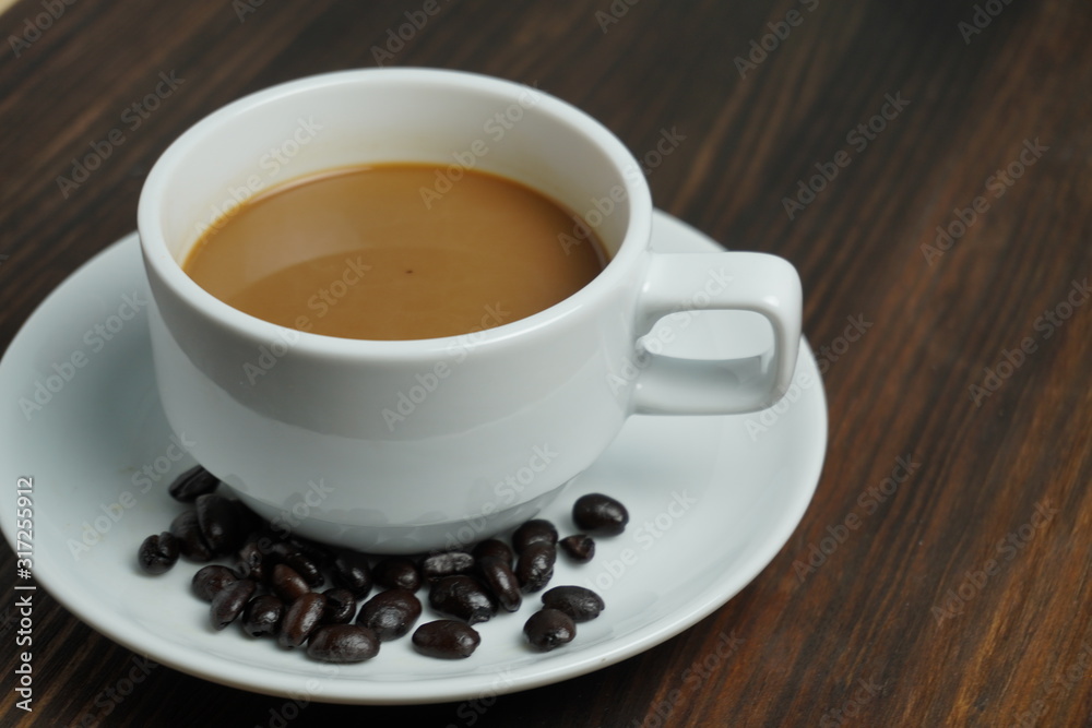 Wall mural black coffee in a white pitcher on an old wooden table