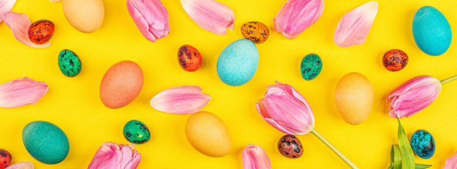 Stylish background with colorful easter eggs isolated on yellow background with pink tulip flowers. Flat lay, top view, mockup, overhead, template