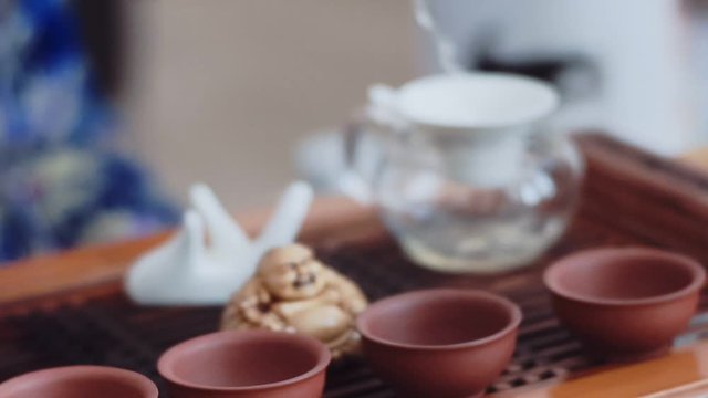 On a wooden table there is a set for the Chinese tea ceremony, in gaiwan poured fragrant green tea