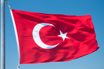 Turkish flag flutters against the blue sky.