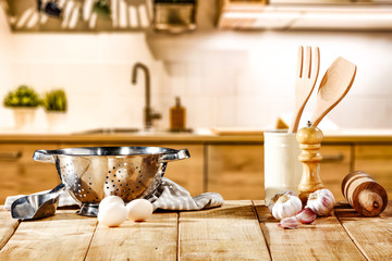 Brown kitchen furniture with empty space on table.Copsy space and kitchen board.White cook hat and few kitchen utensils.Free space for your product and morning time. 