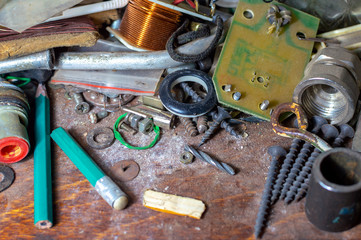 A pile of various rusty bolts, retainers, nuts and other scrap on a dirty shelf in a craftsman