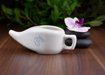 Ceramic Neti pot for nasal cleansing stock images. White ceramic Neti pot with OM symbol. Neti pot still life with zen stones and orchid flower stock images. White Neti pot on a wooden background